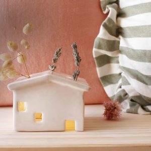 Casita de cerámica con luz interior y flores en el techo